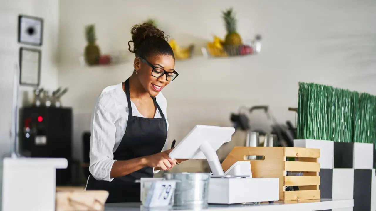 Café staff member taking an order on a POS terminal at the counter