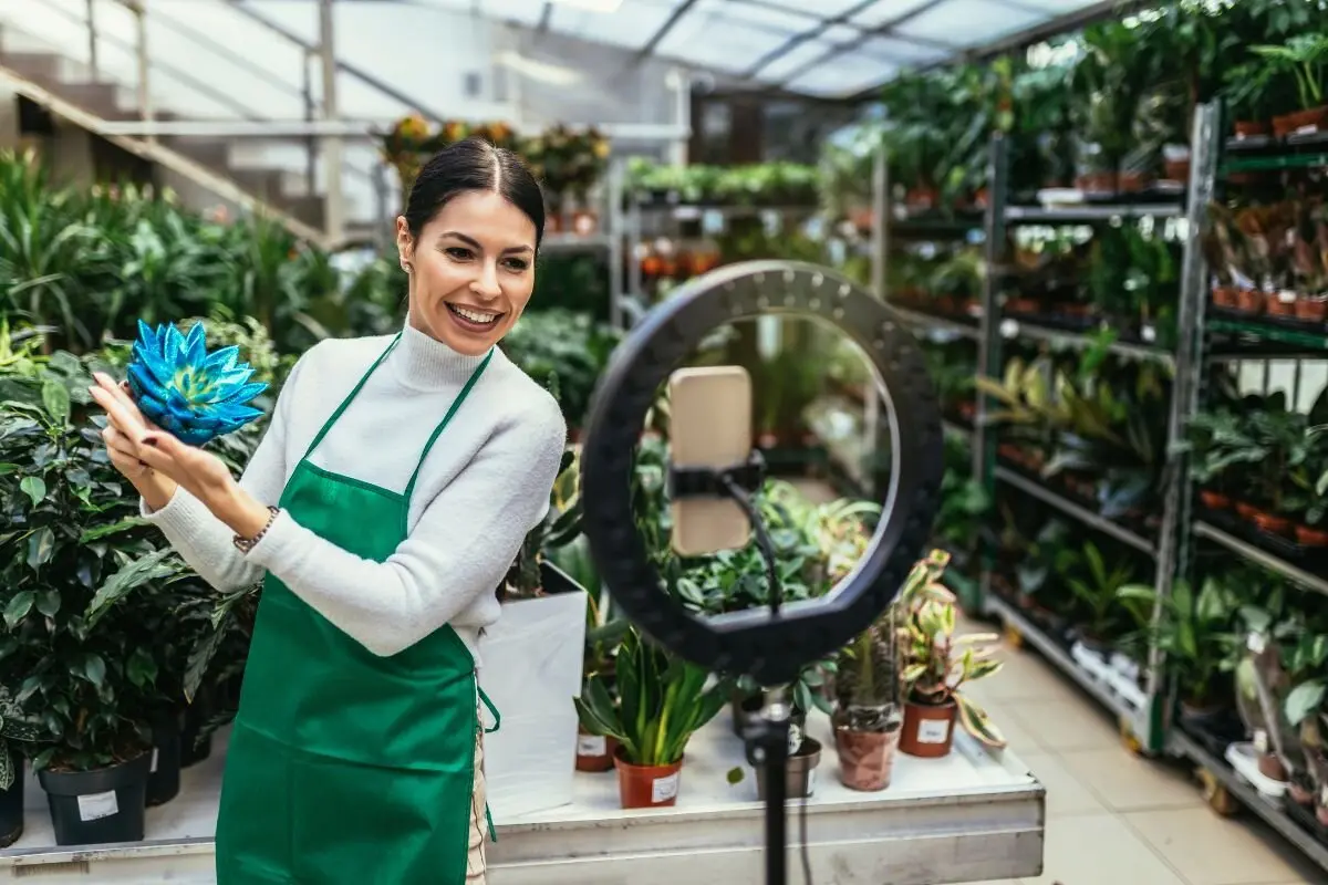 Small business owner live streaming product sale with ring light in plant shop